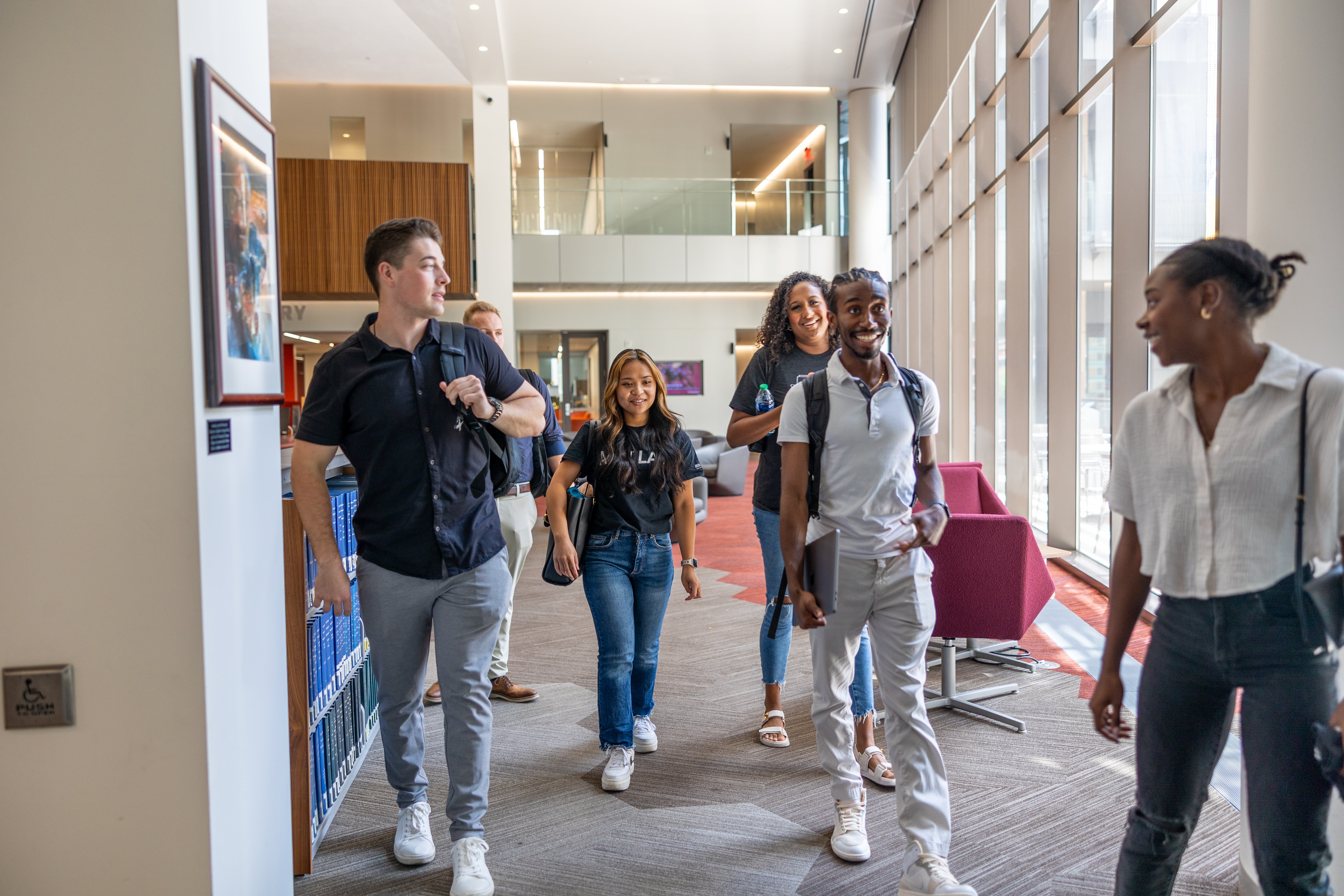 Students walking and laughing together in the Law Library at ASU Law.